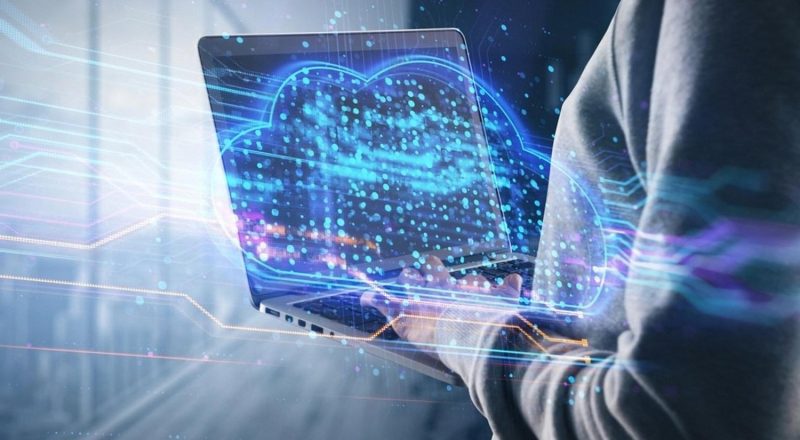 Person holding a laptop with a glowing cloud icon, representing cloud migration for UAE businesses